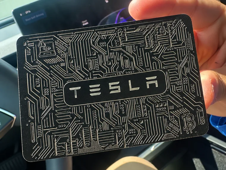 A real engraved Tesla key card with a circuit-board design, held inside a Tesla